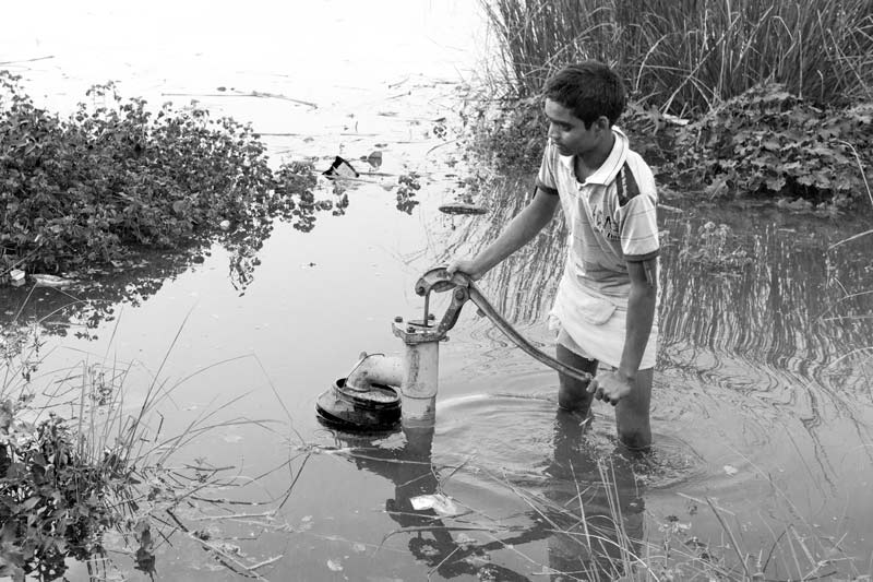 Rural Drinking Water Challenges - Taking unsafe drinking water from a handpump submerged under flood waters in Bhojpur district, Bihar